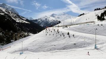 A snowy ski slope with a ski lift and a mountain backdrop.