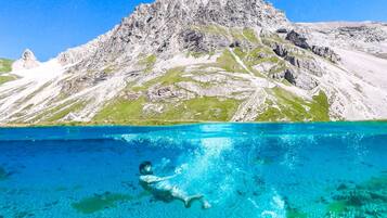Nadador en aguas azules cristalinas con una montaña al fondo.