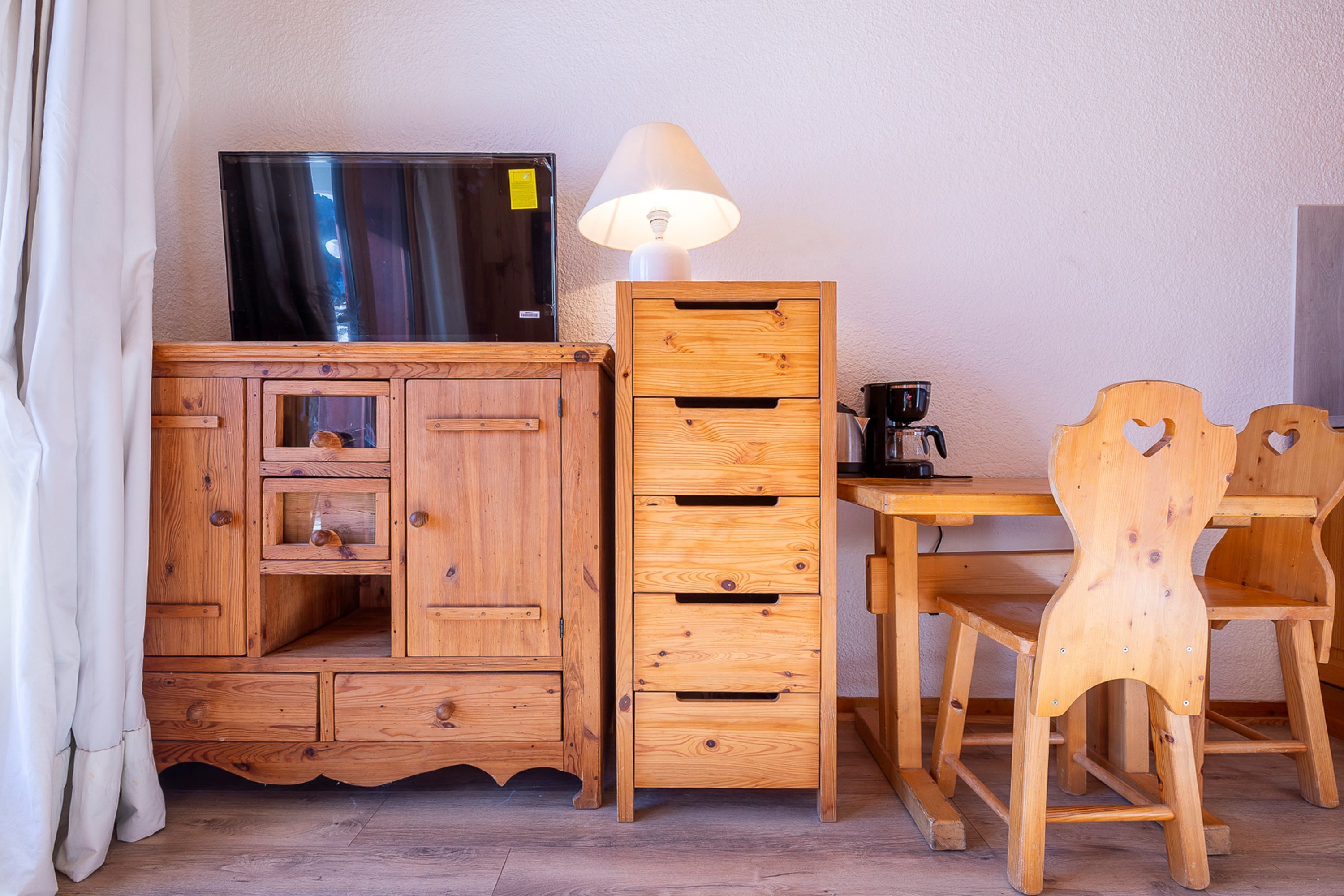 A wooden cabinet with a television on top, a lamp, and a wooden chair.