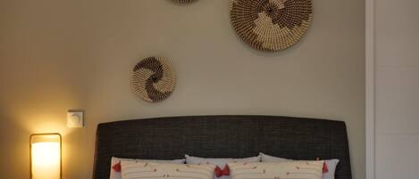 A neatly made bed with white linens and patterned pillows, a dark headboard, and three circular wall decorations.