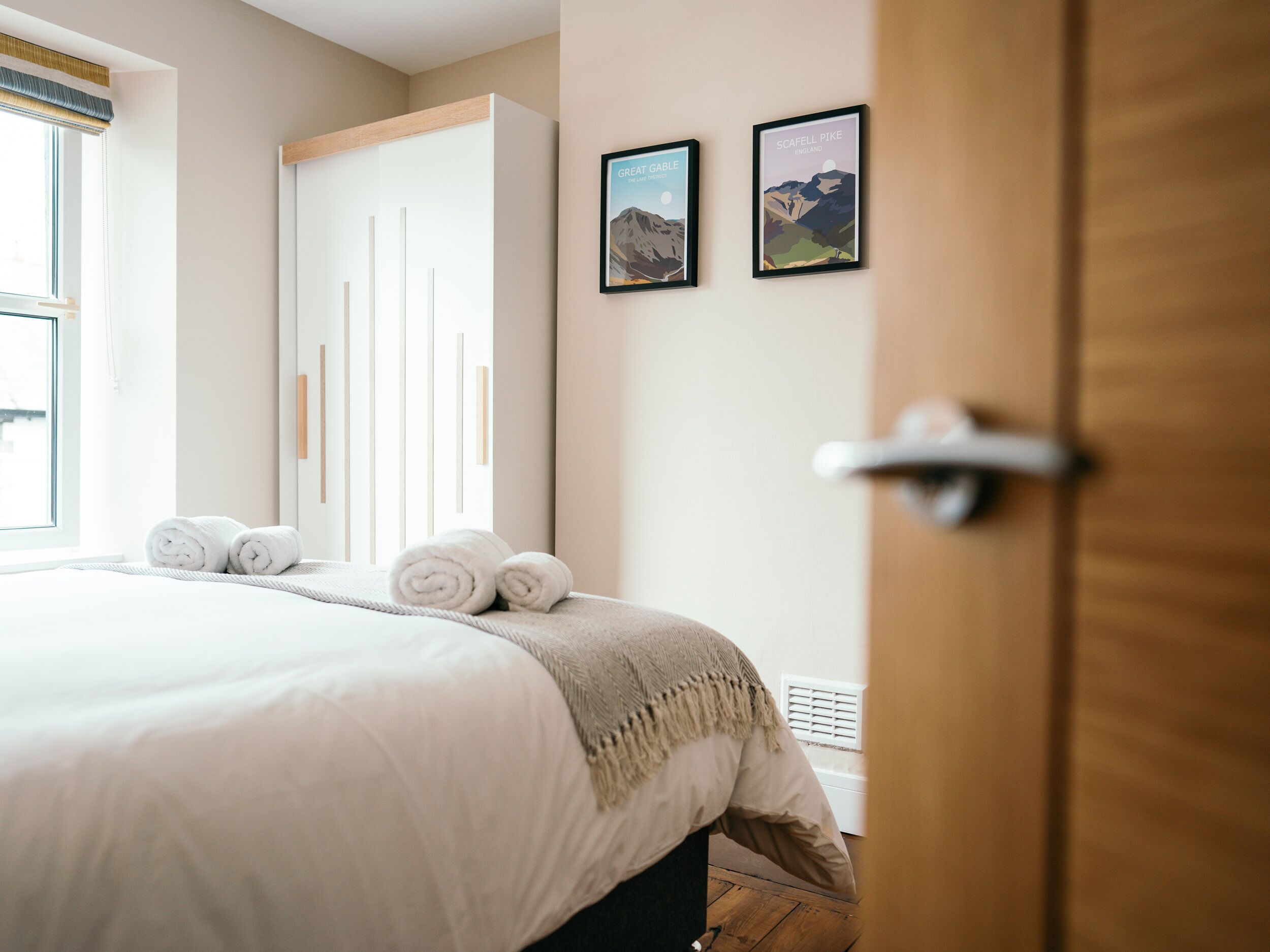 A hotel room with a bed, a wardrobe, and two framed pictures on the wall.