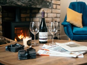 A table with a bottle of wine, two glasses, a candle, and some magazines. - The Deekabout (Keswick)