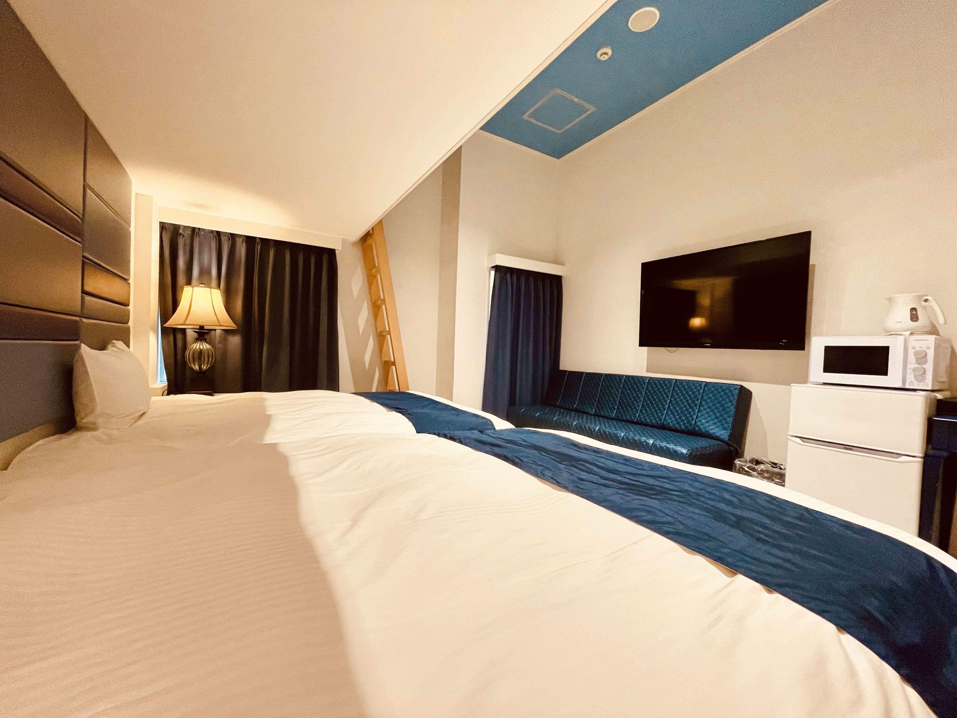 A hotel room with a large bed, a desk with a flat-screen TV, a microwave, and a coffee maker.