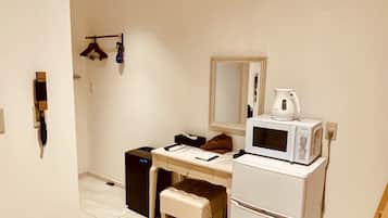 Una cocina compacta con microondas, refrigerador y un taburete pequeño.