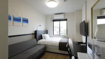 Una habitación de hotel con cama, sofá, televisor y aire acondicionado.