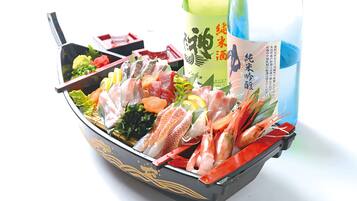 Un bateau japonais traditionnel rempli de divers fruits de mer et une bouteille de saké.