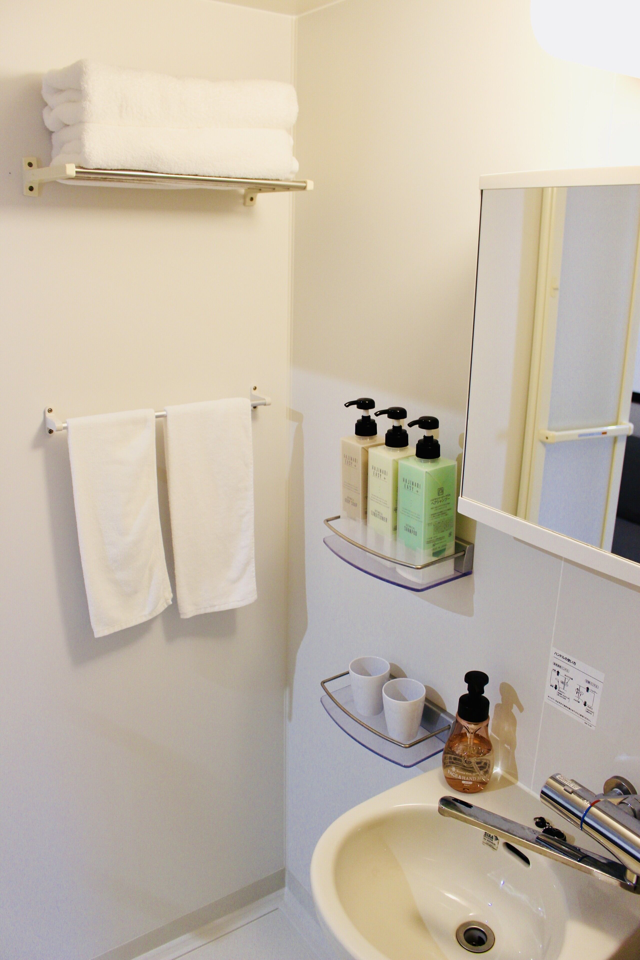 A bathroom with a sink, mirror, towel rack, and shelves with toiletries.
