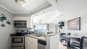 Une cuisine moderne équipée d’appareils électroménagers en acier inoxydable, un coin repas avec vue et un ventilateur de plafond.