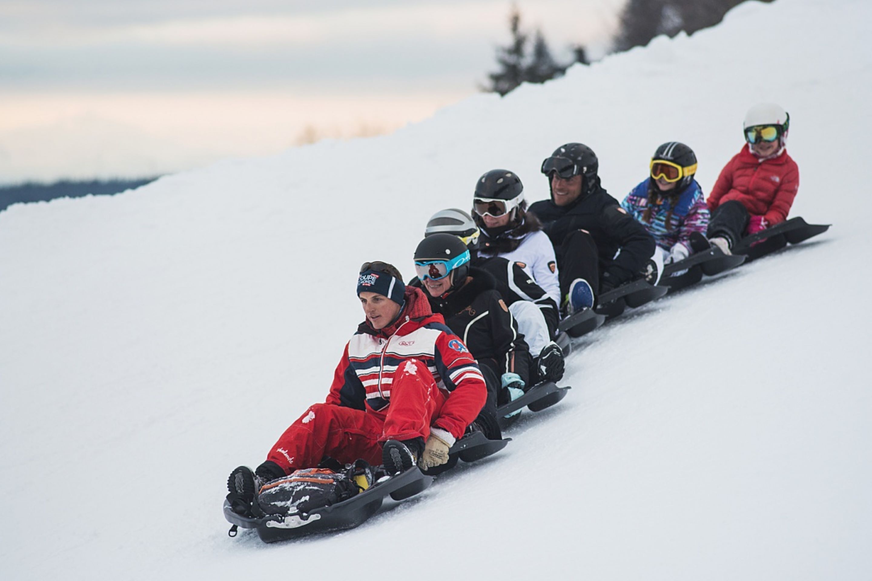 A group of people sledding down a snowy slope.