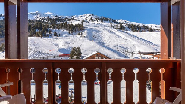 A wooden balcony with a view of a snow-covered mountain and ski slopes. - Résidence Le Pralin - Méribel-Mottaret (Les Allues)