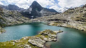 Ein Bergsee, umgeben von felsigem Gelände und einem markanten Gipfel in der Ferne.