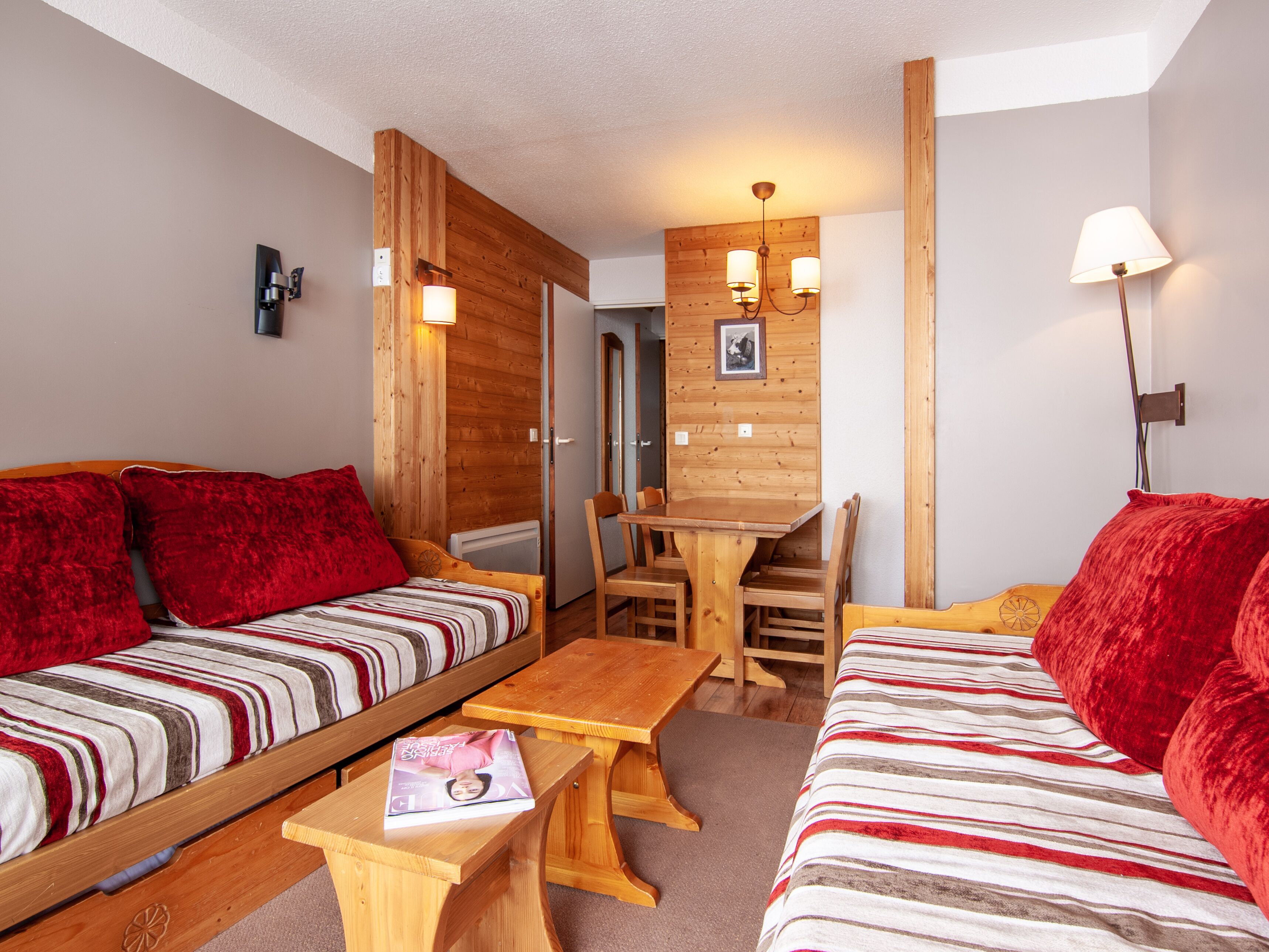 Una habitación acogedora con dos camas de madera, una mesa de madera y una silla de madera.