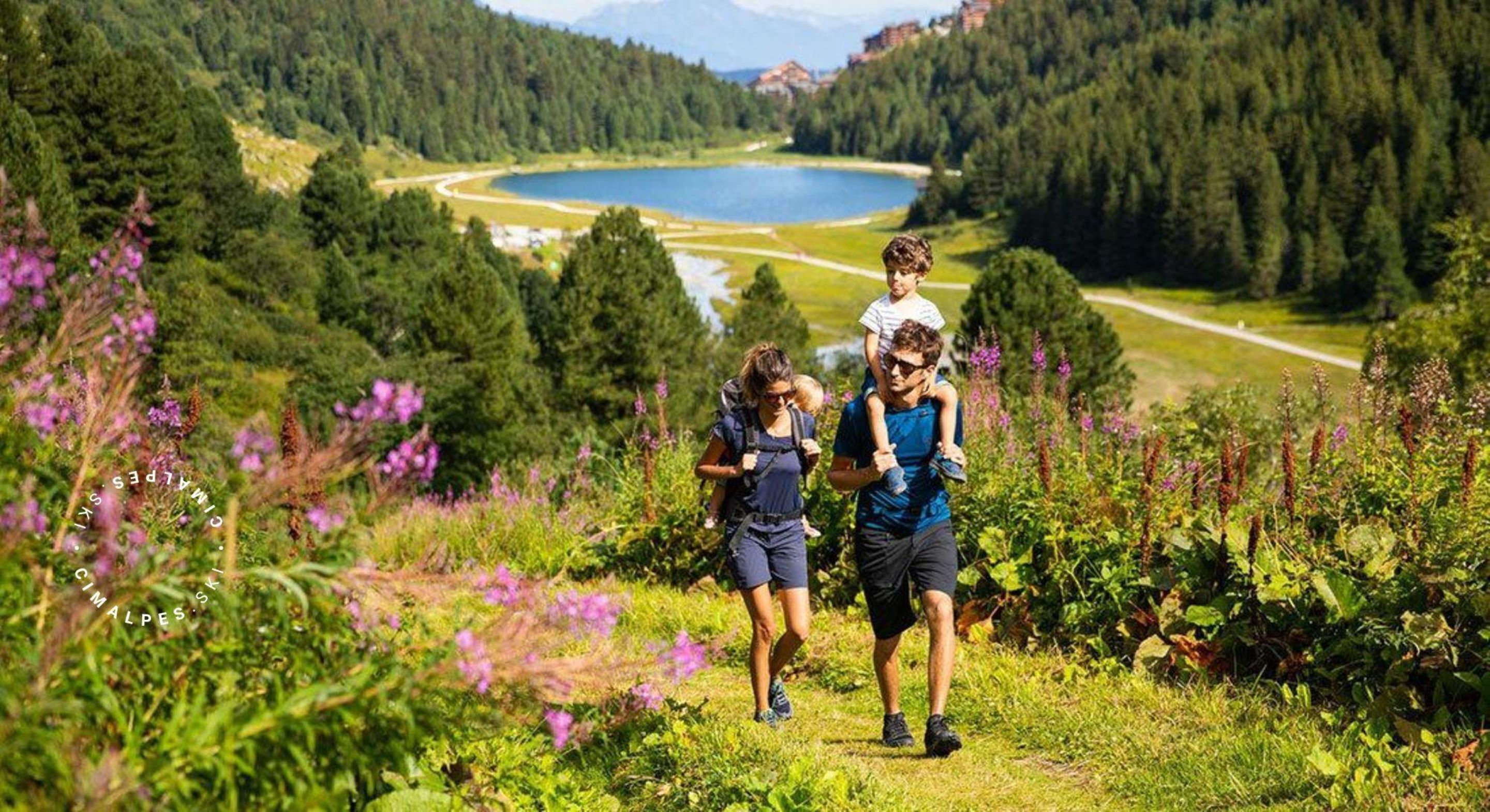Un grupo de personas caminando por una zona montañosa, con un lago al fondo.