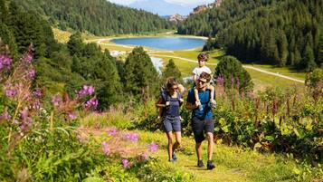 A group of people hiking in a mountainous area with a lake in the background.
