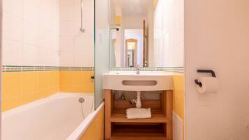 Une salle de bain avec une baignoire, un lavabo et un miroir.