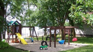 A playground with a swing set, slide, and tire swing. - Maryview Beach House, Maryview Beach House (La Grand Township)