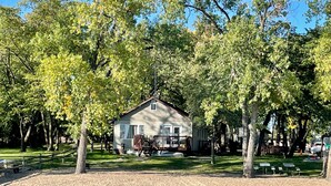 A cabin surrounded by trees, with a sandy area in front and a body of water nearby. - Maryview Beach House, Maryview Beach House (La Grand Township)