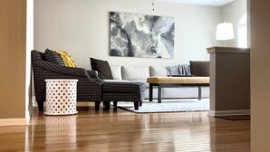 Un salon doté d’un ventilateur de plafond, d’un grand tableau abstrait et d’un plancher en bois.