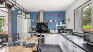 Een moderne keuken met witte kasten, een houten eettafel en een groot raam.