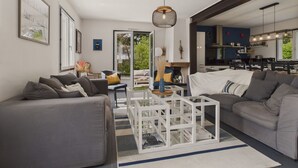 Een moderne woonkamer met grijze banken, een witte salontafel en uitzicht op de keuken.