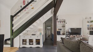 Een moderne woonkamer met een trap, een bank, een televisie en een boekenkast.