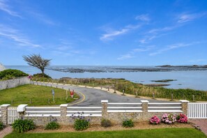 A coastal road with a stone wall, a tree, and a view of the sea.