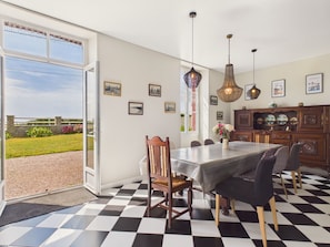 A dining area with a checkered floor, a table with chairs, hanging pendant lights, and framed pictures on the wall.