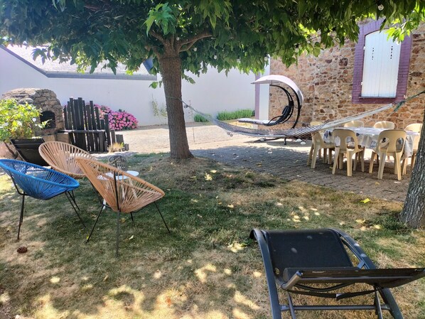 An outdoor seating area with a hammock, wicker chairs, and plastic chairs. - Family house with sea view in Assérac (Assérac)
