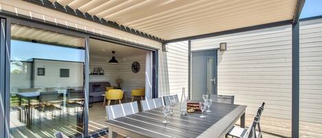Enjoy al fresco dining under a covered area with a large table for four and matching chairs.