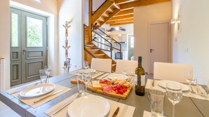 Ein Essbereich mit Holztisch, gedeckt für eine Mahlzeit, einer Treppe und Blick ins Freie.