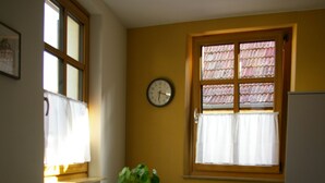A small dining area with a white table and two chairs, a potted plant, and a clock on the wall. - Im Alten Löwen (Hochstadt (Pfalz))