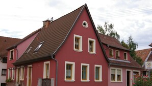 A red and white house with a sloped roof, a small porch, and a visible number 30 speed limit sign. - Im Alten Löwen (Hochstadt (Pfalz))