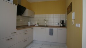 A compact kitchen with white cabinets, a microwave, a sink, and a coffee maker. - Im Alten Löwen (Hochstadt (Pfalz))