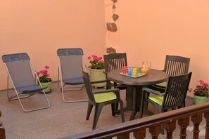 A patio with a round table, six chairs, and potted plants. - Gîtes du Couvent, "Oriel"—a beautiful apartment in the historic center of Kaysersberg (Kaysersberg)