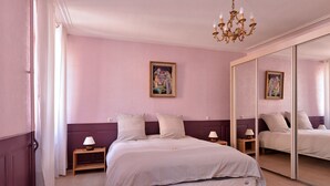 Camera da letto con un letto, comodini, un lampadario e un grande specchio.
