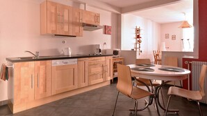 Una cucina moderna con mobili in legno, forno a incasso e zona pranzo con tavolo e sedie rotonde.