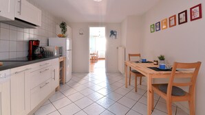 Eine moderne Küche mit weißen Schränken, einer schwarzen Arbeitsplatte und einem Essbereich mit einem Holztisch und Stühlen.