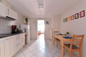 A modern kitchen with white cabinets, a black countertop, and a dining area with a wooden table and chairs. - Gîtes du Couvent, "Geiler" beautiful apartment in historic center of Kaysersberg (Kaysersberg)