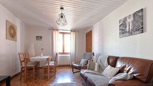Ein gemütliches Wohnzimmer mit einem Holzespeisetisch, einem Ledersofa und einem gemusterten Teppich.