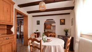A dining area with a round table, wooden chairs, a chandelier, and a view into the kitchen. - Gîtes du Couvent, "Schlossberg" beautiful apartment in the historic center of Kaysersberg (Kaysersberg)