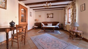 A cozy living room with a wooden dining table, a sofa, a chandelier, and a large rug. - Gîtes du Couvent, "Schlossberg" beautiful apartment in the historic center of Kaysersberg (Kaysersberg)