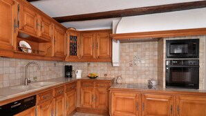 A kitchen with wooden cabinets, a Bosch dishwasher, a microwave, and a double oven. - Gîtes du Couvent, "Schlossberg" beautiful apartment in the historic center of Kaysersberg (Kaysersberg)