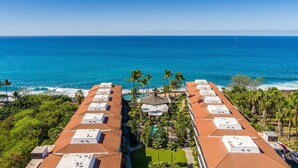 A resort with multiple buildings, a pool, and a view of the ocean.