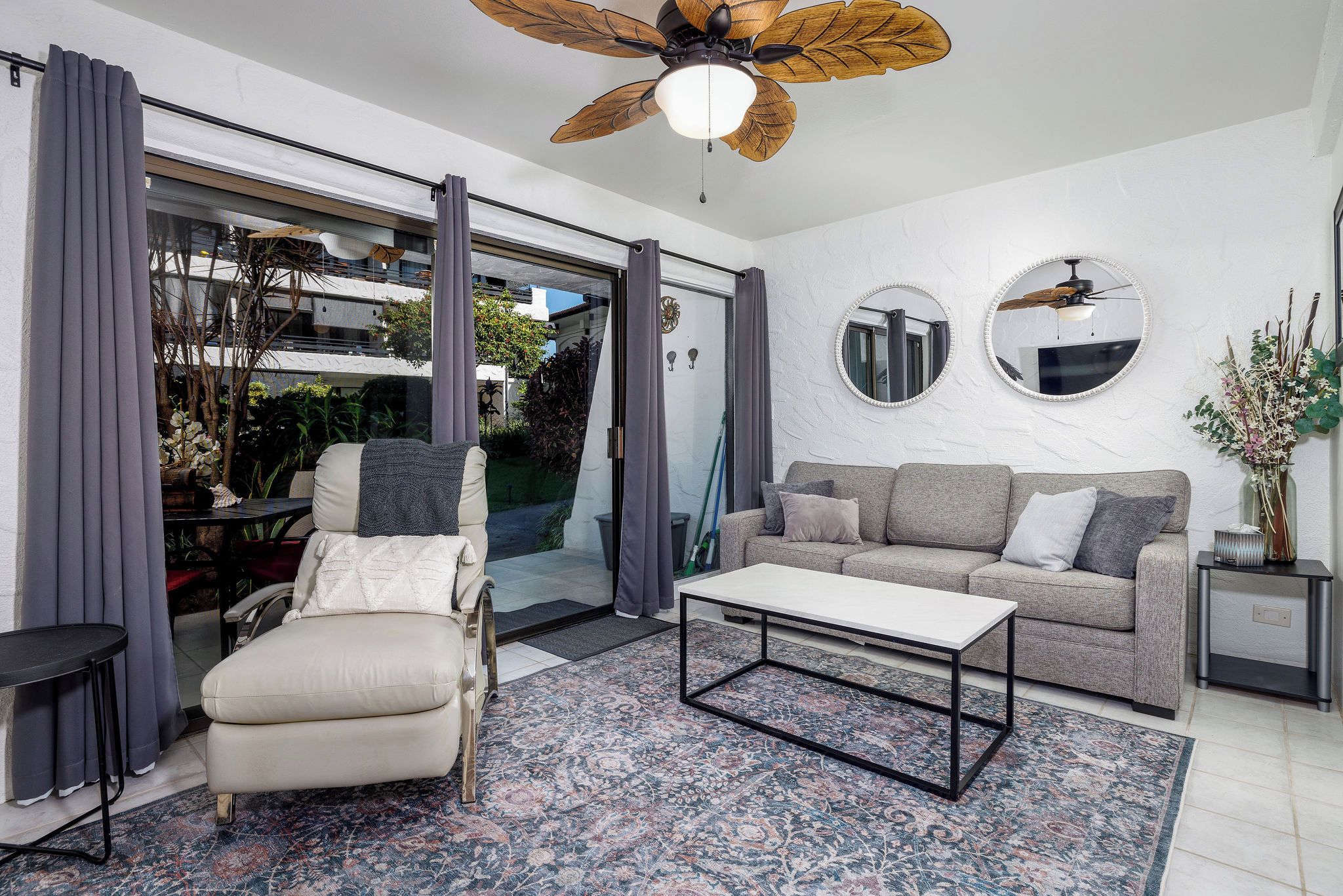 Una sala de estar moderna con sofá, sillón, mesa de centro y ventilador de techo.