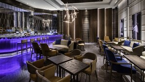 Un área de bar moderna con mostrador, asientos y una lámpara geométrica original.