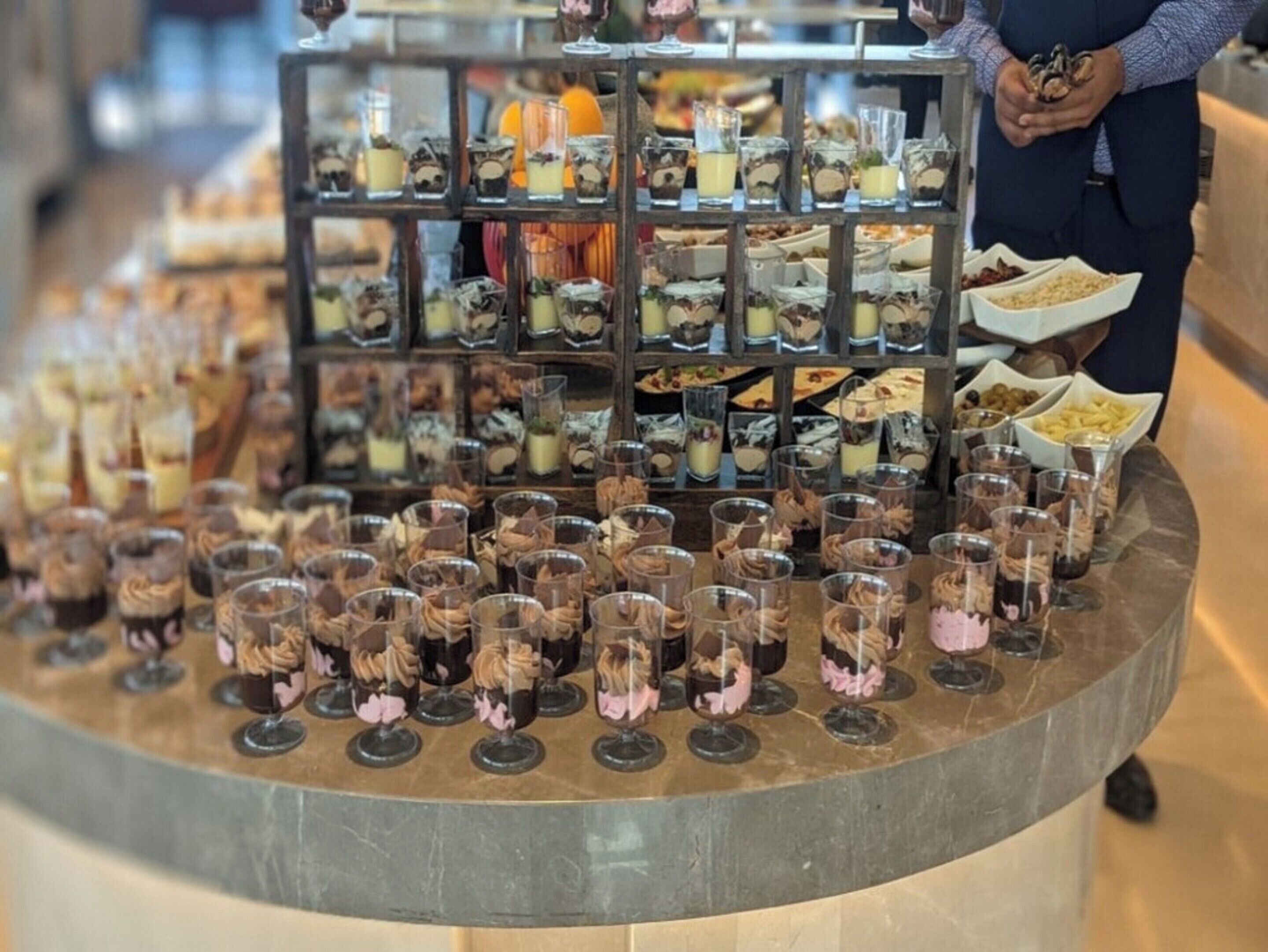 Una mesa con postres variados y una persona sirviendo.