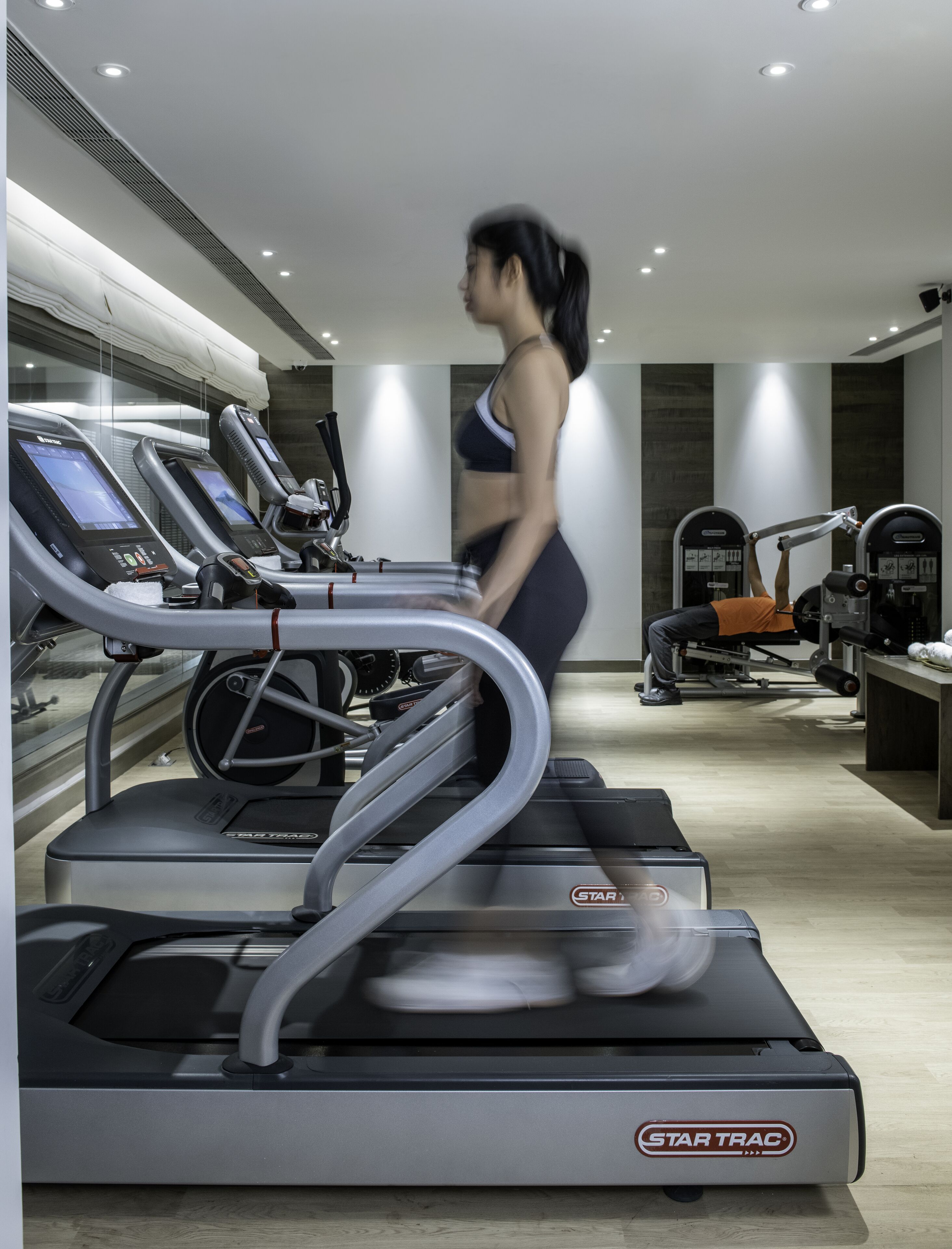 A gym with treadmills, weight machines, and a mirrored wall.