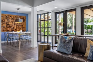 Un salon moderne avec un coin repas, de grandes fenêtres et une vue sur l’extérieur.