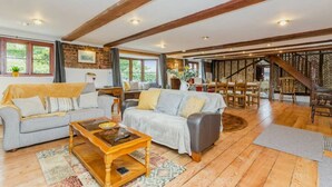 A spacious living area with two sofas, a coffee table, and a dining area with wooden furniture.