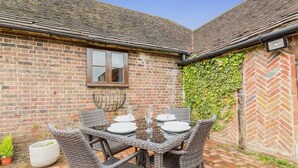 A brick patio with a table set for four, surrounded by wicker chairs.